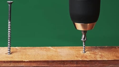 CloseUp of Screw is Unscrewed From a Wood Board with a Screwdriver
