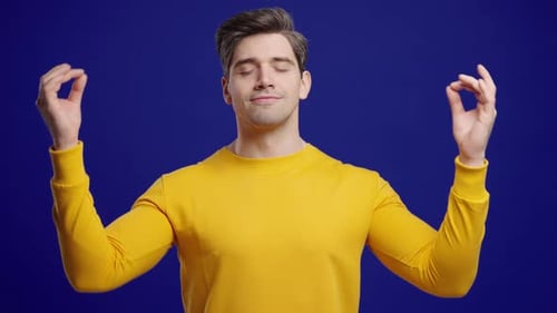 Relaxed Man Meditating Against a Blue Background