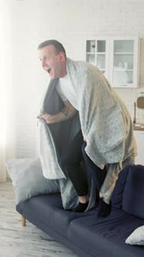 Happy man on bed. Young man waking up and began to joy waving blanket.