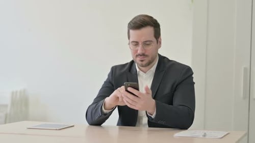 Businessman Browsing Internet on Smartphone in Office
