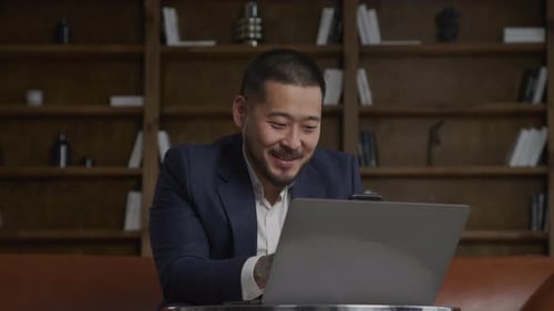 Man in Suit Waving Hand in Greeting Gesture Using Smartphone