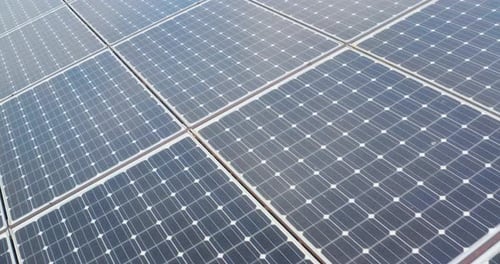 Aerial close up shot of photovoltaic sun panels used for renewable clean energy in a sunny day.
