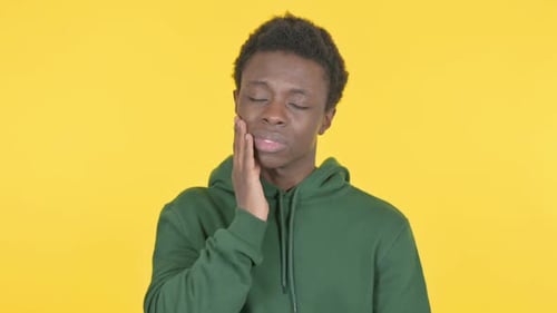 Jeune homme africain ayant mal aux dents sur fond jaune