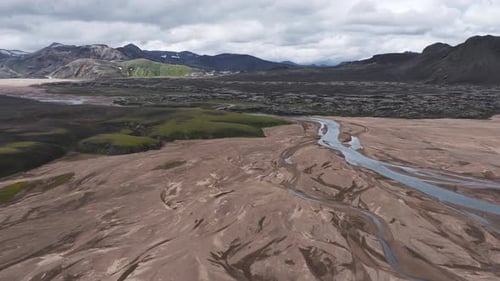 Aerial View of Iceland's River Volcanic Terrain and Snowy Peaks