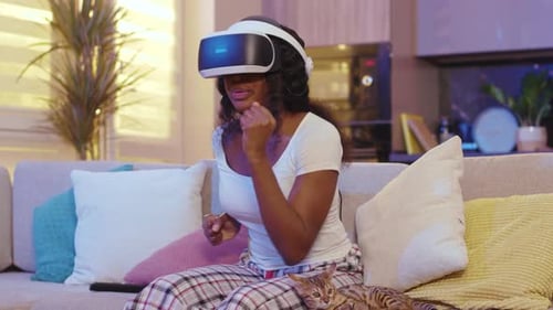 Enthusiastic woman using VR headset on couch
