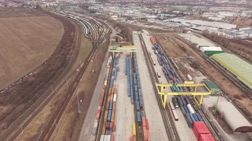 High angle drone view of a large intermodal freight terminal with rows of cargo containers and