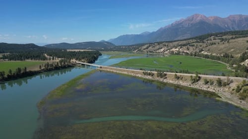 Aerial View of a Scenic Valley With River, Bridge, Highway, Fields, Forests, and Mountains