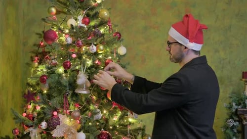 Adult Decorates Christmas Tree with Festive Ornaments