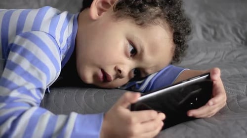 Boy Focused Watching Smartphone Lying on Bed