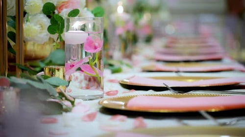 Shot of Served Table with Cozy Golden Plates and Flowers As a Part of Decoration at the Party in