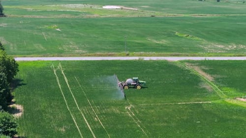 Agricultural Sprayer Tractor Spreading Chemical Pesticide Fertilizer on Growing Crops on Farm Field