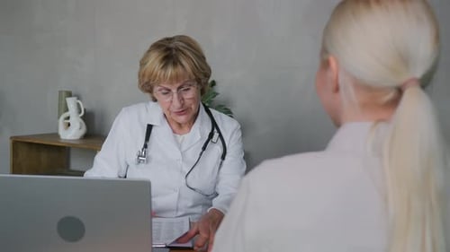 Doctor Reviews Medical Records With Patient at Office