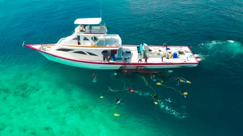Fishermen on a White Boat Take Out Fishing Nets with Caught Fish Near a Local Island Ukulhas in the