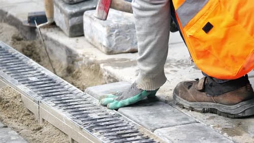 Worker Installing Paving Stones with Hammer
