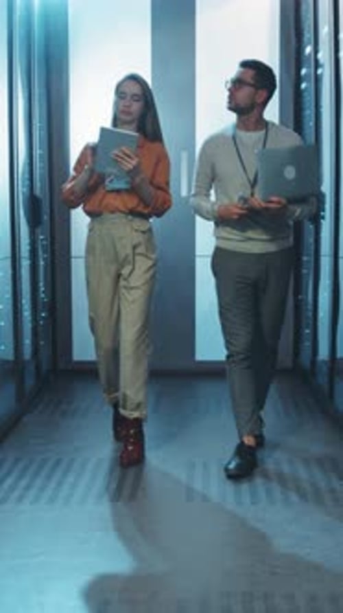 Man and Woman Walk Through Server Room
