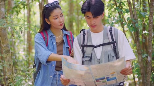 Asian man and woman backpacker friend travel in forest wild together.