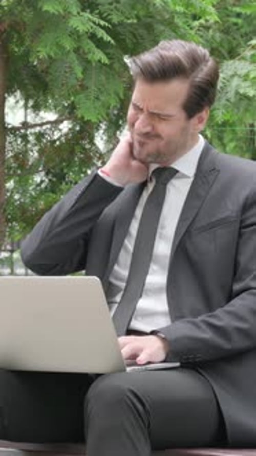 Man in Suit Sitting on Bench with Laptop
