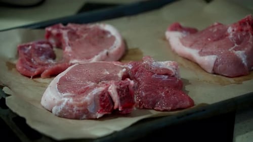 A woman places pieces of raw fresh meat on baking paper.