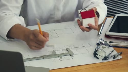 Female Architect Or Engineer use Vernier Caliper to measure the model house. Architectural Concept.