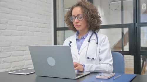 Hispanic Female Doctor Working on Laptop in Office