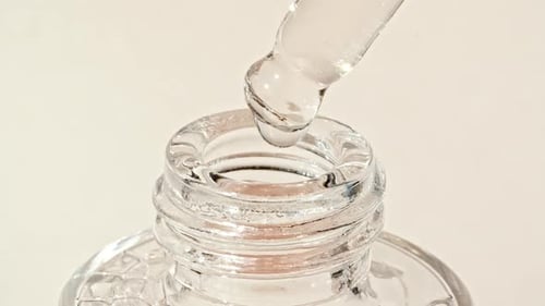 Clear Serum Dripping from Pipette into Glass Bottle