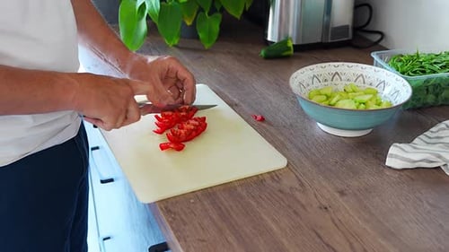 Un homme coupe des tomates rouges pour une salade fraîche dans la cuisine de la maison