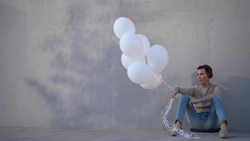 Young Adult with Balloons Listens to Music in City