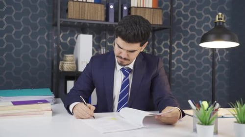 Businessman examining and signing paperwork in his office.