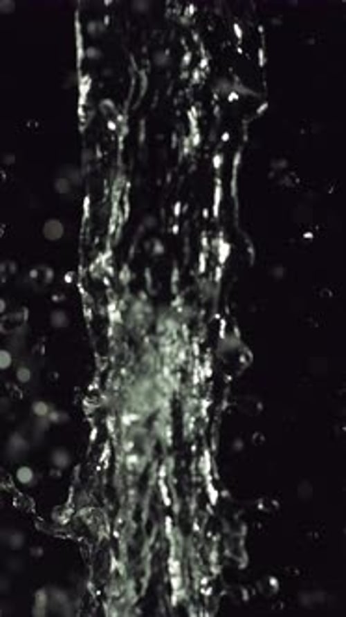Close-Up Of Water Splashing Upwards Against Dark Backdrop