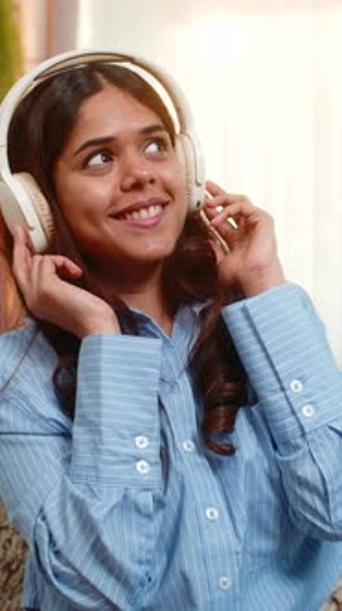 Woman Enjoys Music with Headphones Indoors, Relaxing at Home