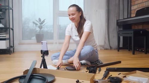 Woman Assembling Furniture Kit at Home Using Phone