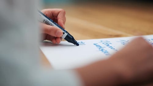 Strategic Thinking: Woman's Hand Engaged in Business Brainstorming with Blue Marker on wooden table