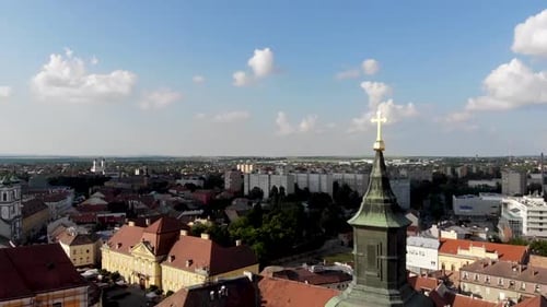 Ascending drone shot behind the top of the church with a cross looking over the city