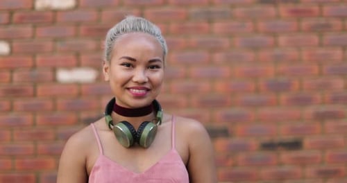 Smiling young woman poses in front of brick wall