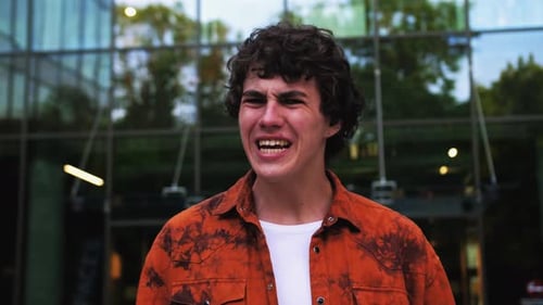 Portrait of Young Caucasian Angry Guy Yells Directly Into the Camera Men's Emotions Outdoors Modern