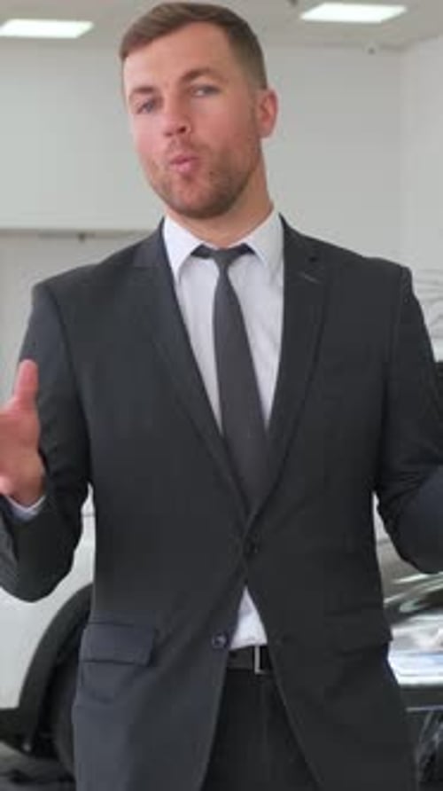 Man in Suit Trousers Gesturing in Front of Car Showroom Vertical Video