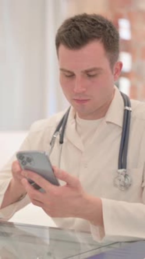 Male Doctor Using Smartphone in Clinic, Vertical Video