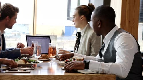 Business People Using Laptop During Working Lunch In Restaurant