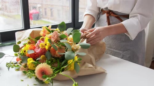 Florist Arranging Colorful Flower Bouquet at Table