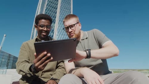 Men Using Tablet Outdoors by Modern Building