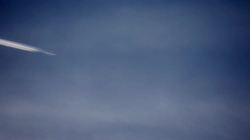 Airplane Soaring Across Blue Sky with Contrail