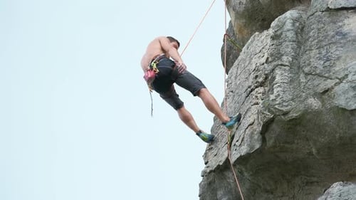 Young Man Descending Down Steep Wall of Rocky Mountain Male Climber Overcomes Challenging Route