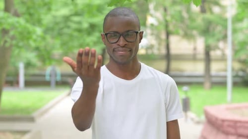 Jeune homme africain faisant signe avec la main à l'extérieur