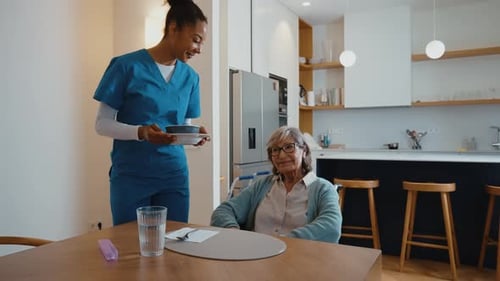 Woman delivers soup to senior woman in wheelchair