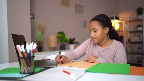 Girl Drawing at Desk with Laptop at Home