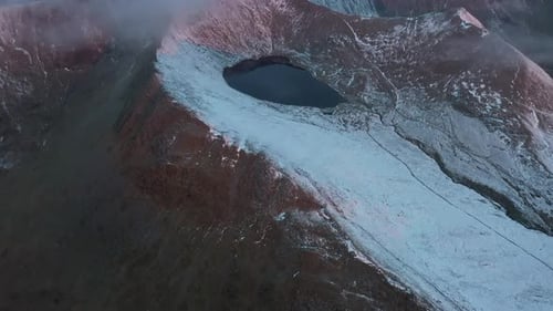 Aerial video of a small lake formed by snow water between the mountains