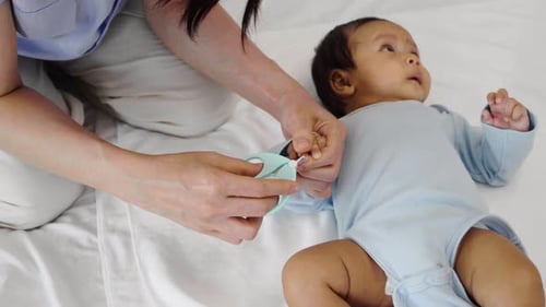 Caregiver Trimming Infant's Nails in a Home Setting