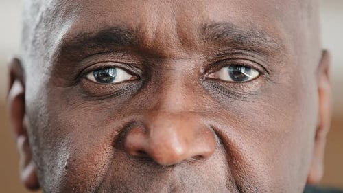 Extreme Closeup Male Wrinkled Face with Dark Skin Eyes Looking at Camera Good Eyesight Successful