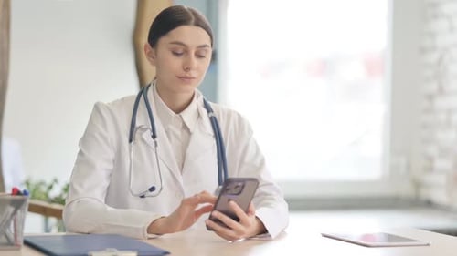 Young Female Doctor Using Smartphone in Clinic