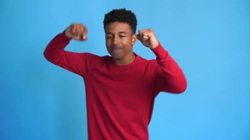 Young Man Dancing and Smiling on Blue Background